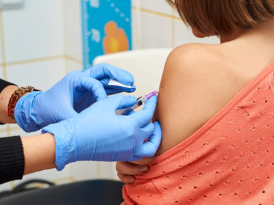 Child receiving vaccination from gloved healthcare professional